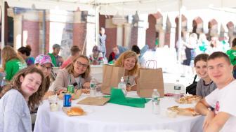 Students smile - sitting around a table outside at convocation