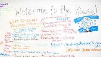 White board covered in song titles, says "Welcome to the House" at the top.