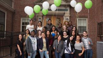 The USI students as freshmen standing outside Alumni Hall with green and white balloons.