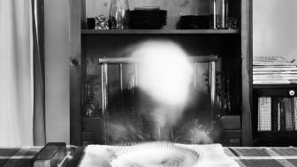 Black and white photo of someone at a dinner table who has been ghosted out