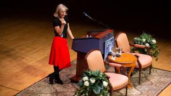 Woman giving a speech on a stage behind a podium