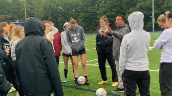Assistant Athletic Director and women's soccer coach Paul Vasconcelos kicks off the alumni game