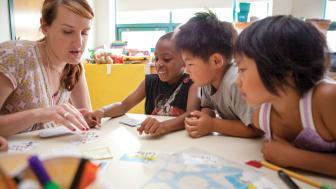children playing cards and learning from their teacher