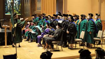 president and doctoral graduates standing on stage