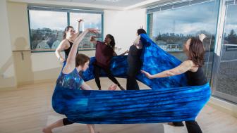 Dancers as part of a movement therapy class in a studio dancing with fabric.