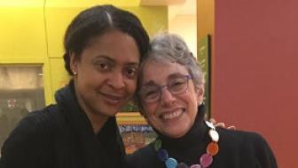 Two women standing together, smiling and posing for a photo