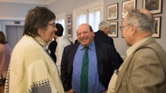Jeff Weiss smiles while talking to two people in Alumni Hall.