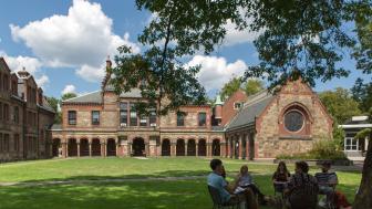 Students sit in chairs in a circle having a class discussion on Lesley's lawn.