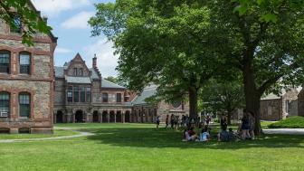 Two circles of students sitting on Lesley's lawn during new student orientation.