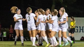 Female soccer players embrace on the field