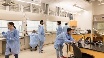 Landscape view of the lab with students working in their lab coats.