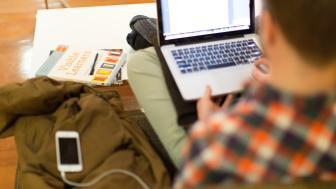 Student studying with computer and book and iPhone