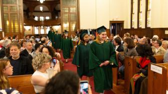 Students in cap and gown proceed into the church.