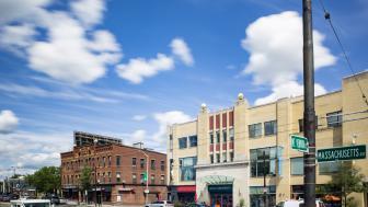 Buildings on a busy city street with blue sky and clouds