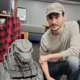 Austin posing next to a large, gray, 3D-printed dragon