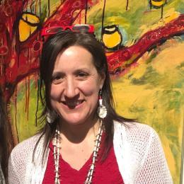 Photograph of Michelle Napoli in front of one of her colorful paintings.