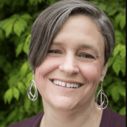 Color photograph from the neck up of Cynthia Platt smiling at the camera. 
