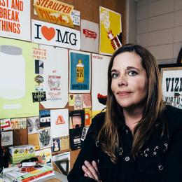 photo of Meta Newhouse standing in front of a wall of stickers
