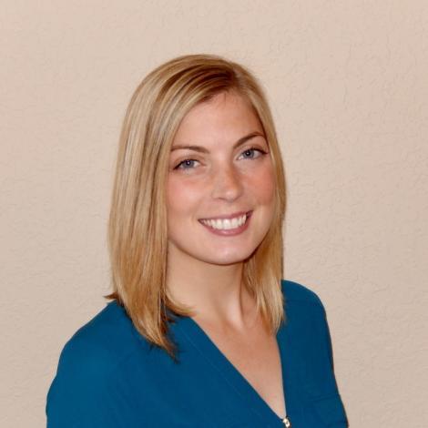 Erin smiling with blue shirt in front of beige background