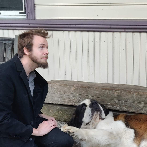 John sitting next to a dog on a bench