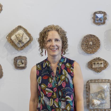 Michelle Lougee standing in front of souvenirs on a white wall