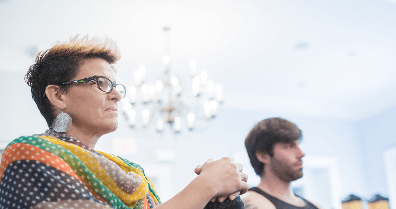 woman sitting down, listening intently to a speaker