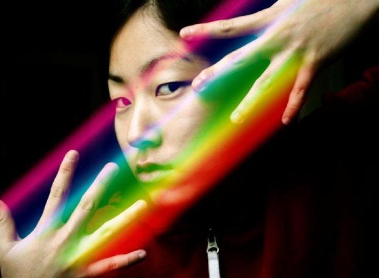 Artistic photo of Noel King with hands around face and prism over her fingers