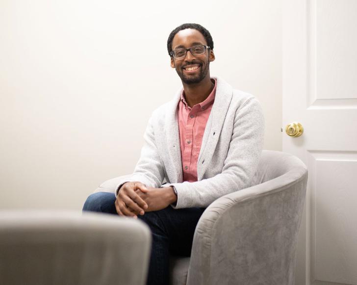 Counseling PhD Alum Brandon Jones, LMHC sitting in his office