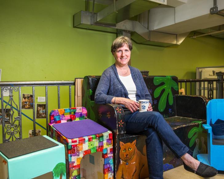 Woman sitting on a colorful chair in a classroom.