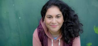 Photograph of Sara Farizan leaning forward smiling at the view. 