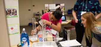 Teacher Lindsay Tosches looks on as a student pours liquid into a beaker.