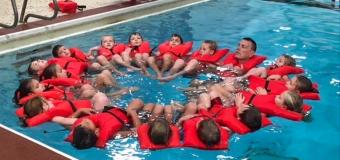 Chris Wendorf and his students in a pool all wearing safety vests and floating in a circle.