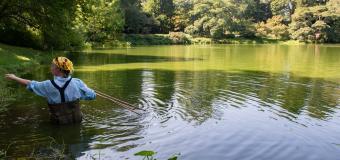 Maria Aliberti Lubertazzi wears waders and stands waist deep in a green pond.