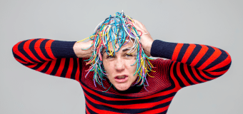 Eileen Powers in a striped shirt and one of the "heads" she and her collaborators designed.