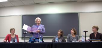 Evelyn Finnegan in 2011 holding a picture book and standing at a table with a panel of people