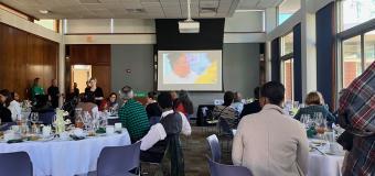 Washburn Lounge, people dinding at tables while video shown on screen