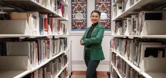 Gloria Noronha standing among the stacks in the library