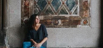 Ingrid Strobe sitting on a stoop with a rustic wall behind her
