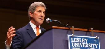 John Kerry speaks in front of a podium while gesturing with his right hand