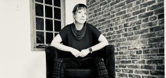 July Westhale sits in an arm chair. Black and white photo