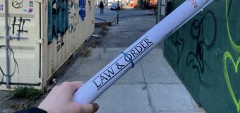 Outside, NYC, hand holding a rolled up paper printed with "Law & Order"