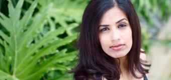 Maria Taher looks up at the camera, ferns are behind her.