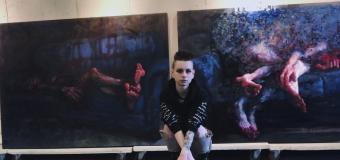 Moriah Faith in front of two of her paintings