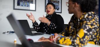 Myisha Rodrigues working with colleagues at a shared desk