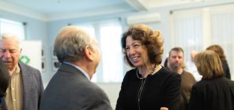 President Janet Steinmayer speaks to a man in a suit at the welcome reception