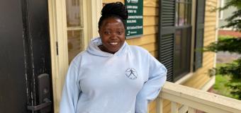 Redempta "Demi" Muhorakeye pictured in front of the yellow 82 Oxford St building on the Lesley campus.