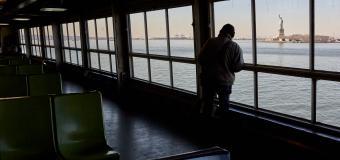 Someone looks out of the window of the Staten Island Ferry. Appears to be early evening.