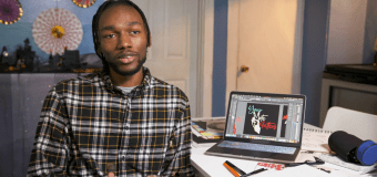 Trevonne Deveaux sitting at his desk with computer featuring design beside him