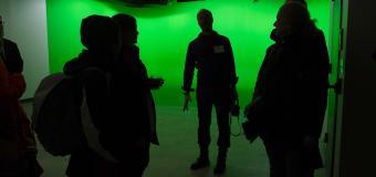 People silhouetted against the lit green room.