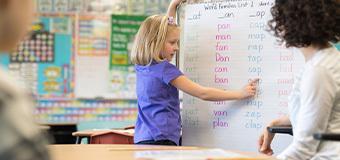 Elementary student works through a vocabulary exercise on a whiteboard in her classroom.